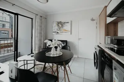 a small kitchen with a black table and chairs at The Blyde Crystal Lagoon Apartment in Pretoria