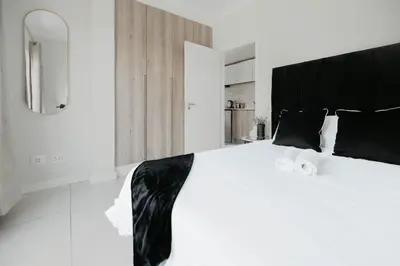 a bedroom with a large white bed with black pillows at The Blyde Crystal Lagoon Apartment in Pretoria