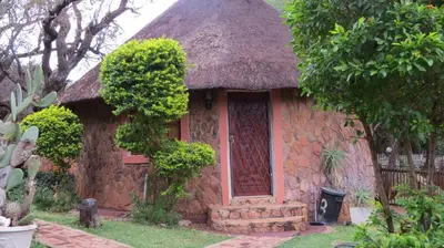 a small stone house with a thatch roof at Amatava Lodge in Mokopane