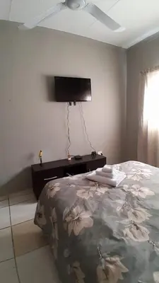 a bedroom with a bed and a flat screen tv at Koshys Haven at Kruger in Malelane