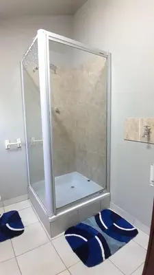 a shower in a bathroom with two blue rugs at Koshys Haven at Kruger in Malelane