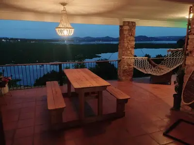 a porch with a wooden table and hammock on a balcony at Wakanda on Hartbeespoort Dam in Hartbeespoort