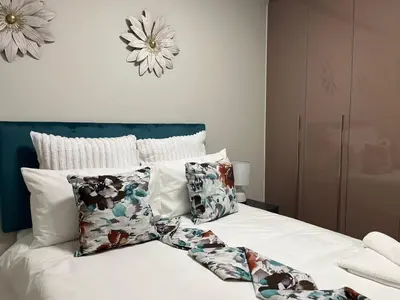 a bedroom with a bed with white sheets and pillows at Ambience Defined in Randjesfontein