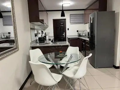 a kitchen with a glass table and white chairs at Ambience Defined in Randjesfontein