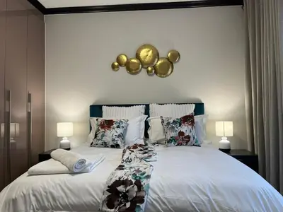 a bedroom with a large bed with gold decorations on the wall at Ambience Defined in Randjesfontein