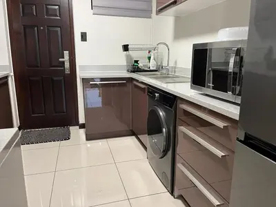 a kitchen with a sink and a dishwasher and a microwave at Ambience Defined in Randjesfontein