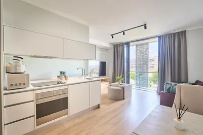 a kitchen with white cabinets and a living room at MaZZ at Ellipse Waterfall in Midrand