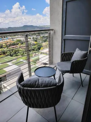 a balcony with two chairs and a table and a view at Menlyn Maine Trilogy Apartment 1101 in Pretoria