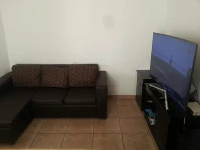 a living room with a black couch and a flat screen tv at Luxury 3-Bedroom Apartment in Midrand in Midrand