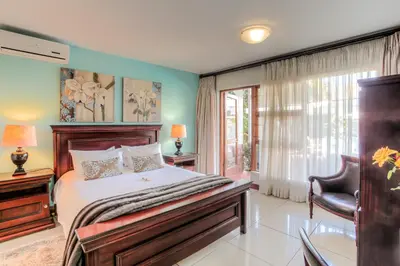 a bedroom with a bed and a chair and a window at Sunninghill Guest Lodges in Johannesburg