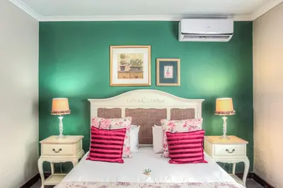 a bedroom with a white bed with a green wall at Sunninghill Guest Lodges in Johannesburg
