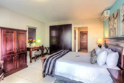 a bedroom with a large bed and a desk at Sunninghill Guest Lodges in Johannesburg