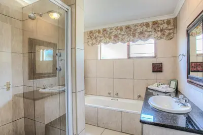 a bathroom with a tub and a sink and a shower at Sunninghill Guest Lodges in Johannesburg