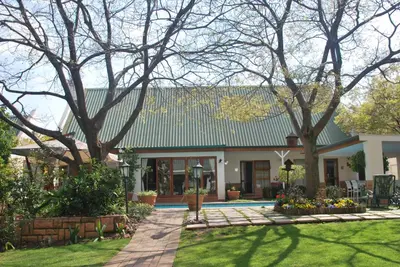 a house with a green roof and a yard at Sunninghill Guest Lodges in Johannesburg
