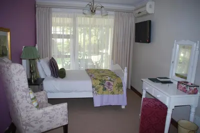 a bedroom with a bed and a desk and a window at Sunninghill Guest Lodges in Johannesburg