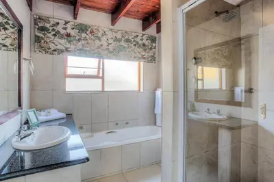 a bathroom with two sinks and a tub and a shower at Sunninghill Guest Lodges in Johannesburg