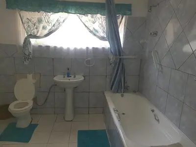 a bathroom with a toilet and a sink and a tub at Cottage1 at Cynthias Country in Hartbeespoort