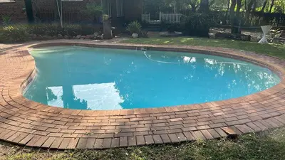 a swimming pool with a brick border around it at Cottage1 at Cynthias Country in Hartbeespoort