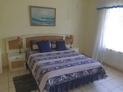 a bedroom with a bed with blue pillows and a window at Cynthias Country Farm Stay 5bedroom in Hartbeespoort