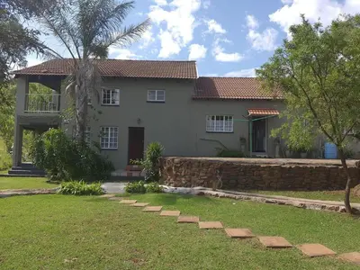 a house with a stone wall in a yard at Cynthias Country Farm Stay 5bedroom in Hartbeespoort
