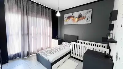 a bedroom with a crib and a large window at Family Elegant Smart Home in Midrand