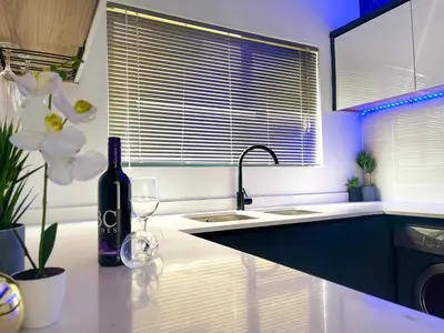 a kitchen with a sink and a bottle of wine and flowers at Family Elegant Smart Home in Midrand