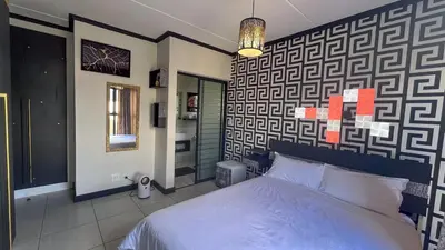 a bedroom with a bed in a room with a wall at Family Elegant Smart Home in Midrand