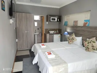 a bedroom with a large white bed and a bathroom at DAMOFUS Guest House in Pretoria