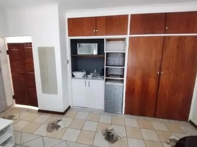 a kitchen with wooden cabinets and a tiled floor at DAMOFUS Guest House in Pretoria