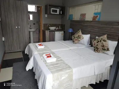 a bedroom with a large bed with white sheets and pillows at DAMOFUS Guest House in Pretoria