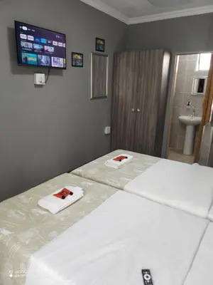 a hotel room with two beds and a tv on the wall at DAMOFUS Guest House in Pretoria