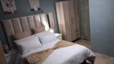 a bedroom with a large white bed with a large headboard at SIMICON Guesthouse in Witbank