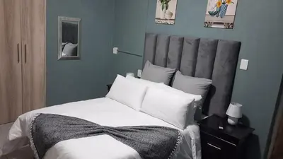 a bedroom with a bed with white sheets and pillows at SIMICON Guesthouse in Witbank