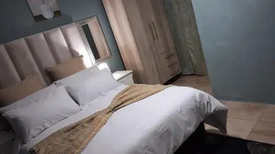 a bedroom with a large white bed and a door at SIMICON Guesthouse in Witbank