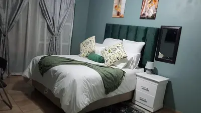 a bedroom with a bed with a green headboard at SIMICON Guesthouse in Witbank