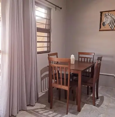 a dining room with a wooden table and chairs at Tjhora Sunset Cottage in Cambridge