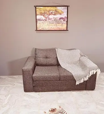 a couch in a living room with a picture on the wall at Tjhora Sunset Cottage in Cambridge