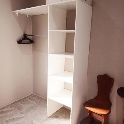 a white book shelf in a room with a chair at Tjhora Sunset Cottage in Cambridge