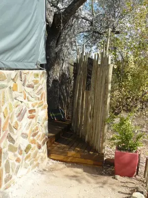 a wooden porch with a fence next to a tree at Tjhora Sunset Cottage in Cambridge