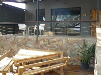 a patio with two picnic tables and a stone wall at Tjhora Sunset Cottage in Cambridge