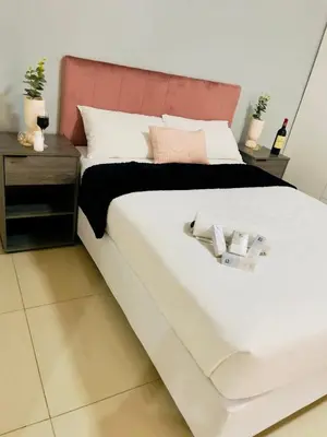 a bedroom with a large white bed with a pink headboard at Rooibok Gardens in Mokopane