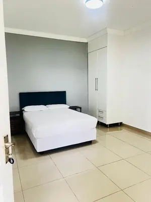 a bedroom with a white bed and a white cabinet at Rooibok Gardens in Mokopane