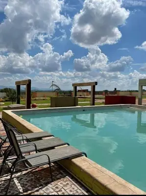 a swimming pool with two lounge chairs at Rooibok Gardens in Mokopane