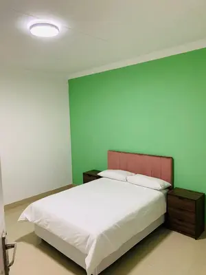 a bedroom with a white bed and a green wall at Rooibok Gardens in Mokopane