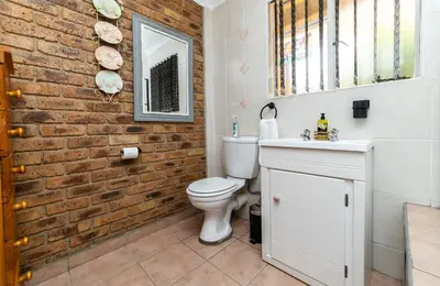 a bathroom with a white toilet and a brick wall at 210 Guest in Kempton Park