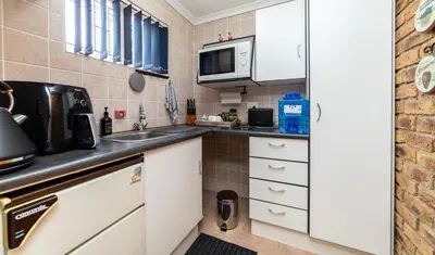 a small kitchen with white cabinets and a microwave at 210 Guest in Kempton Park