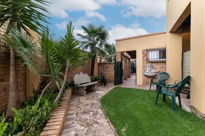 a backyard with a lawn with chairs and palm trees at 210 Guest in Kempton Park