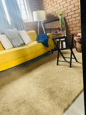 a yellow couch in a living room with a table at Mordern Lil' Love Nest Loft in Midrand in Midrand