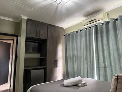 a bedroom with a bed and a window with curtains at JuaMtoto guesthouse in Pretoria