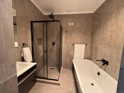 a bathroom with a shower and a tub and a sink at JuaMtoto guesthouse in Pretoria